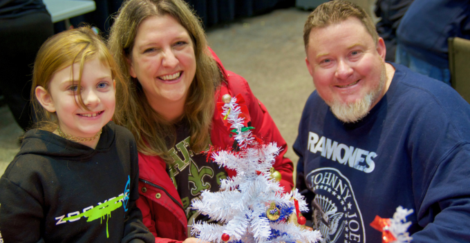 smiling family displaying Christmas tree craft